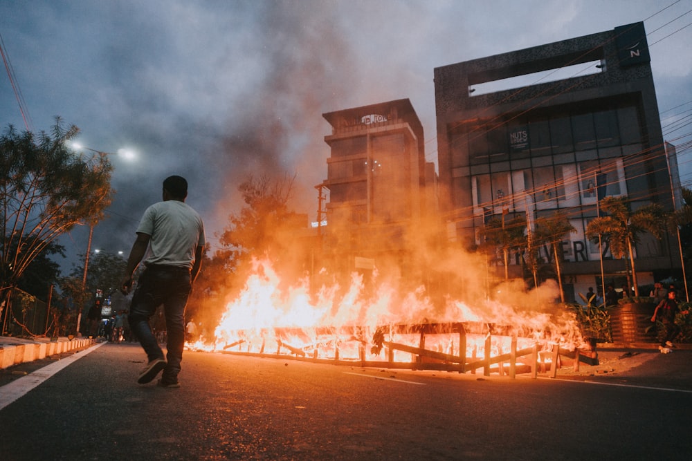man in black jacket standing near burning building