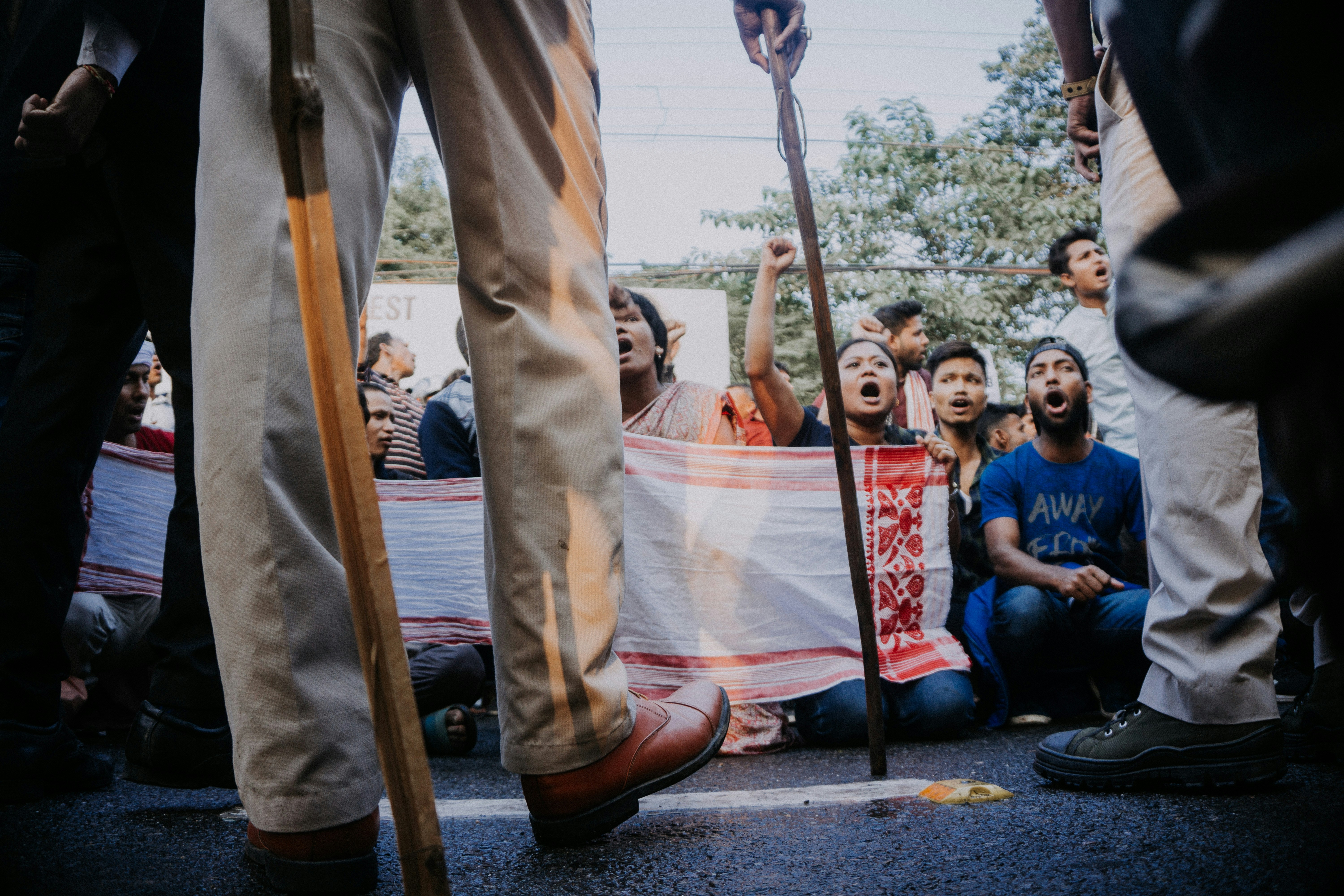 Rahul Gandhi leading a small, peaceful protest outside a modern building, holding a sign that reads 