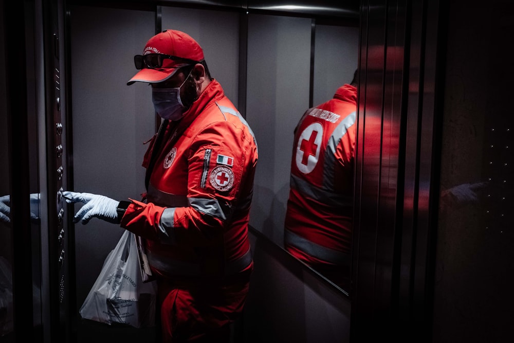 Mann in rot-weißer Jacke neben schwarzer Wand