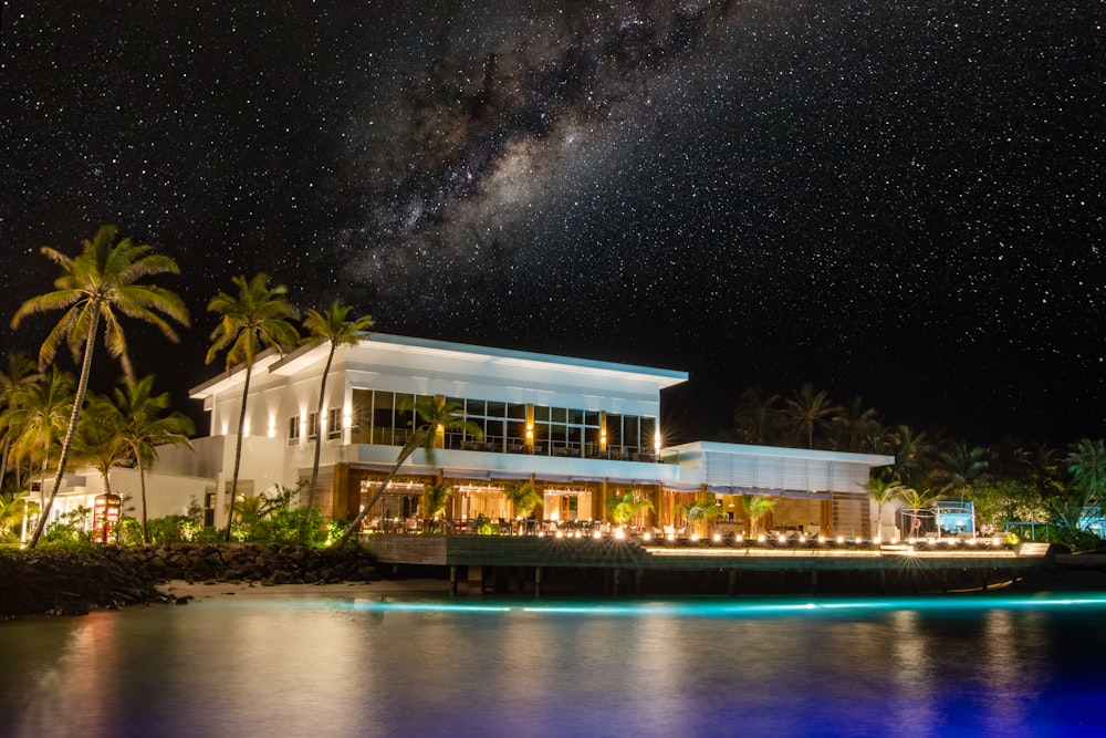 Maison blanche et brune près du plan d’eau pendant la nuit