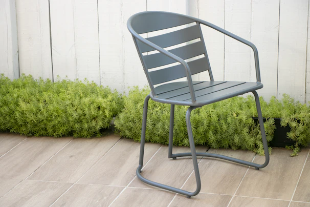 A modern steel patio side table placed beside a lounge chair.