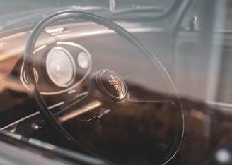 A vintage car dashboard with elegant dials and a leather steering wheel, bathed in warm light.
