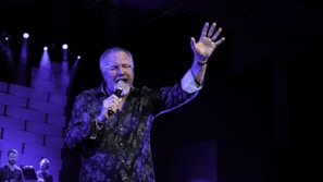 man in black and white floral long sleeve shirt singing