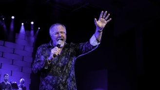 man in black and white floral long sleeve shirt singing