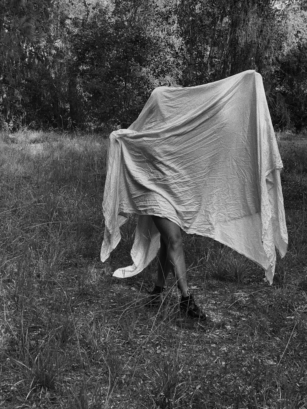 grayscale photo of woman in white dress standing on grass field