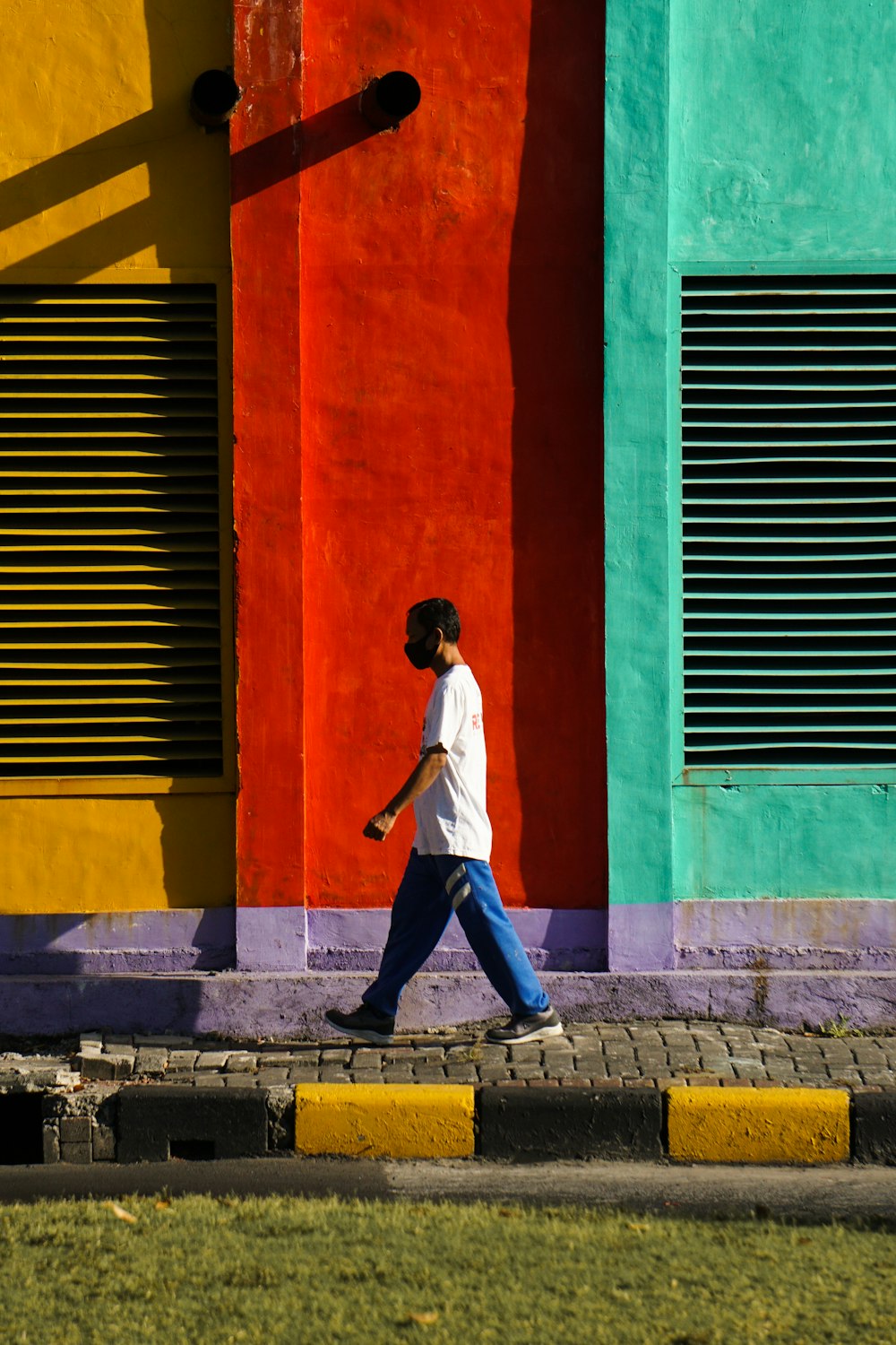 man in white long sleeve shirt and blue denim jeans walking on sidewalk during daytime