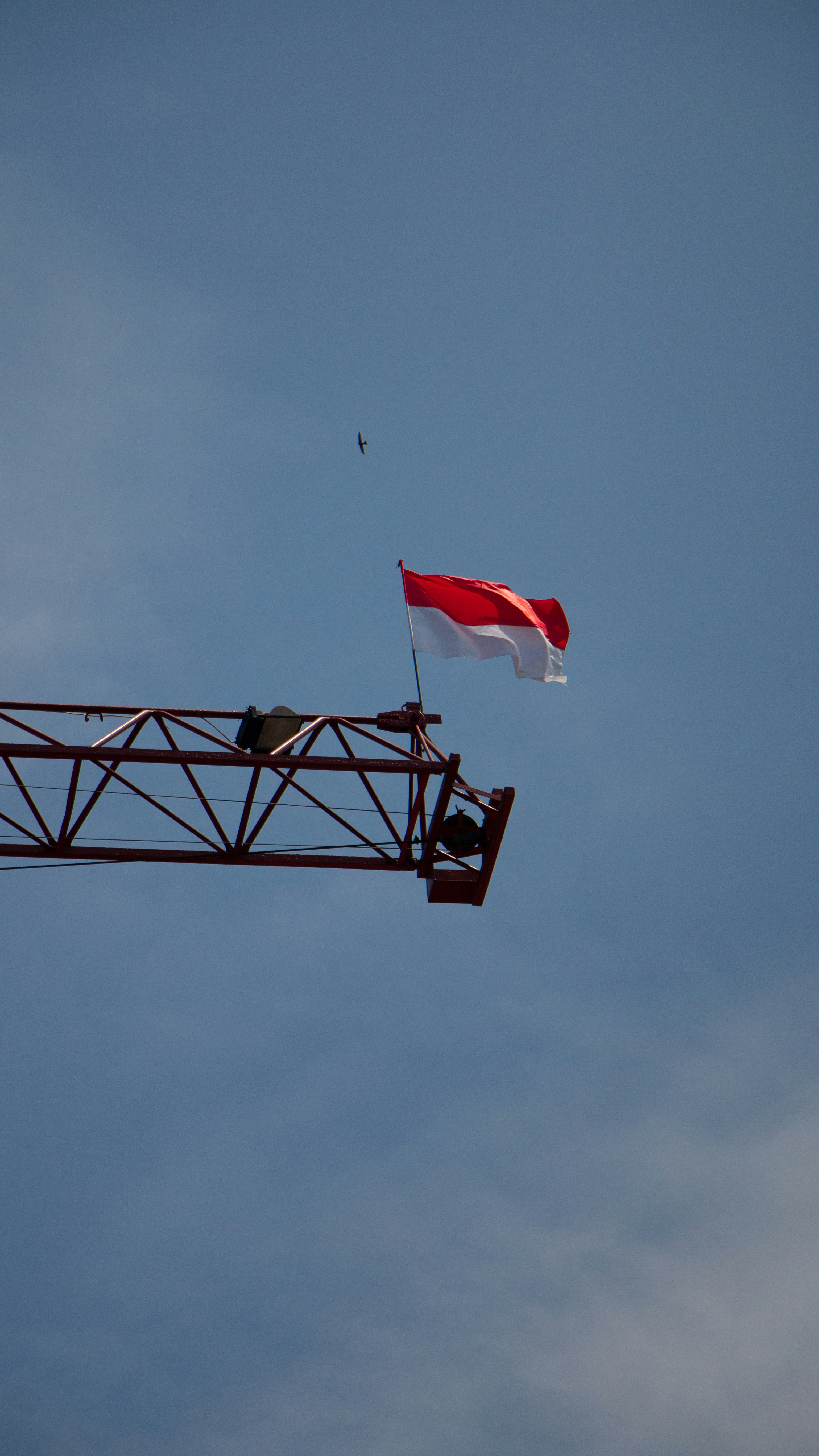 bendera putih dan merah pada tiang logam hitam di bawah langit biru di siang hari