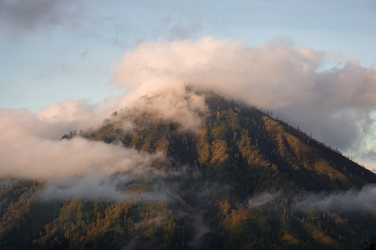 green and brown mountain under white clouds in Ijen Indonesia