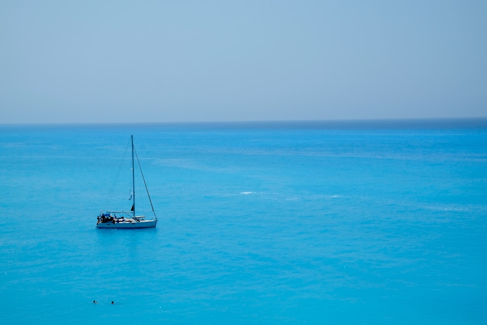 昼間の海上の白と青のヨット