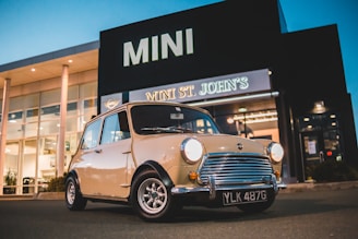 A sleek Mini Cooper car parked in front of the Andi Mini Prioritas dealership building.
