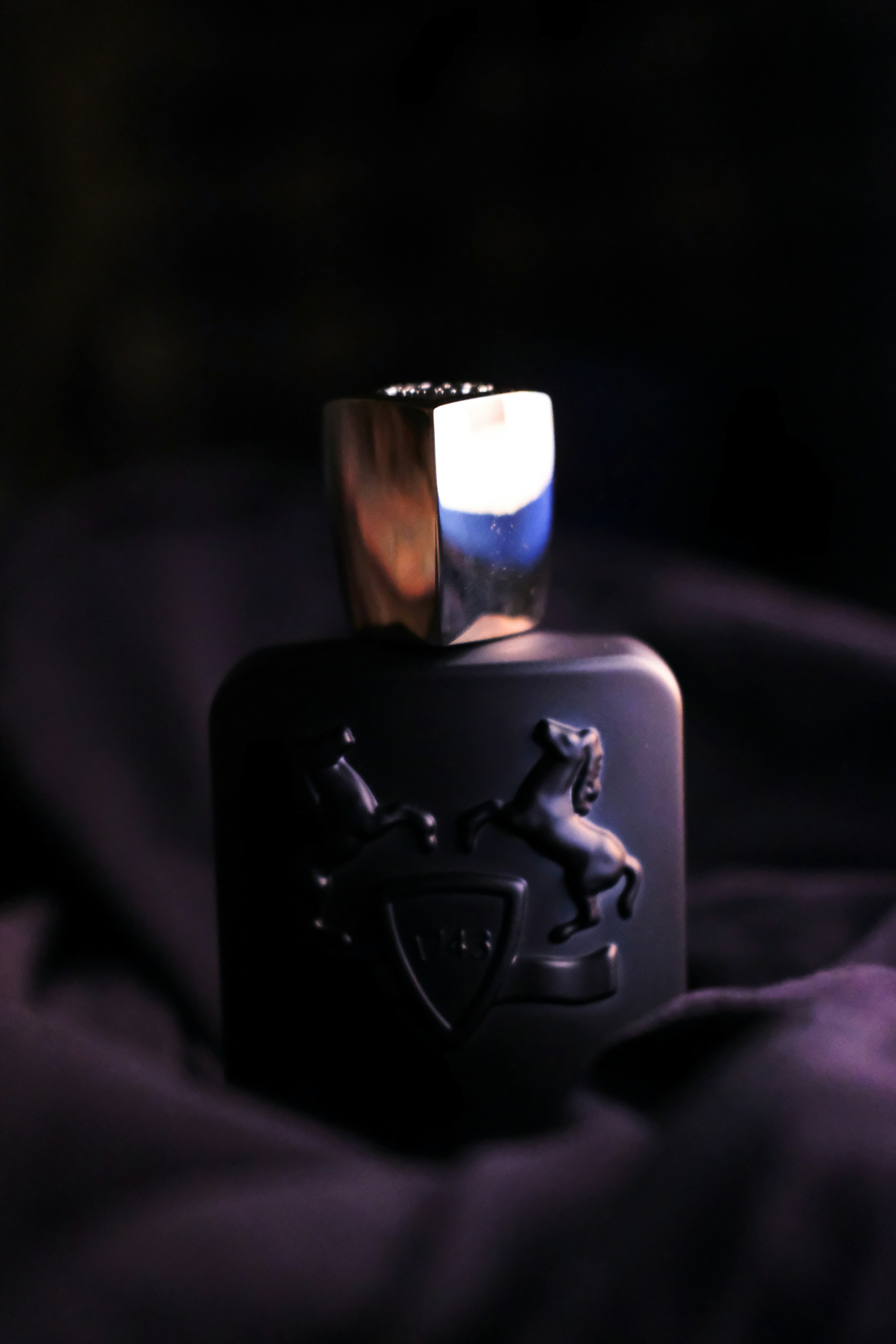 Golden-hued luxury perfume bottle on rich purple silk fabric with scattered saffron threads