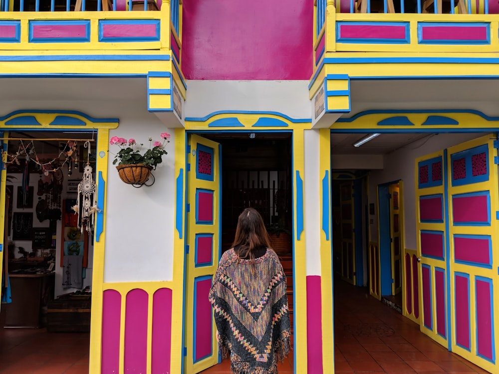 woman in black and white long sleeve shirt standing beside yellow blue and pink painted wall