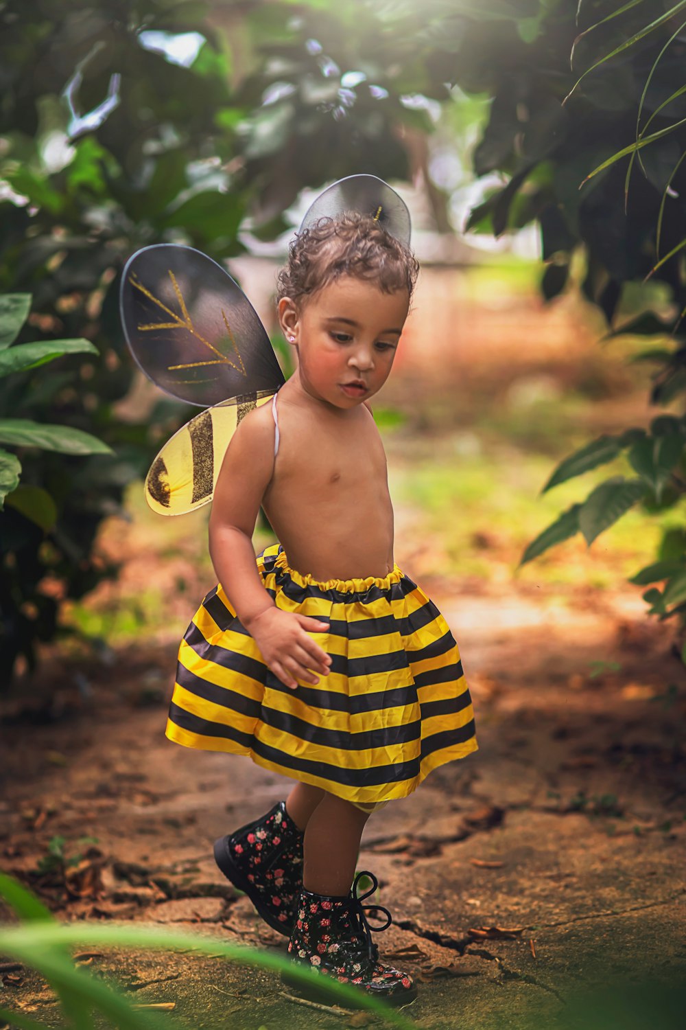 girl in yellow and black stripe dress standing near green leaf tree during daytime