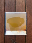 Smooth yellow slime resting on a wooden surface with natural light.