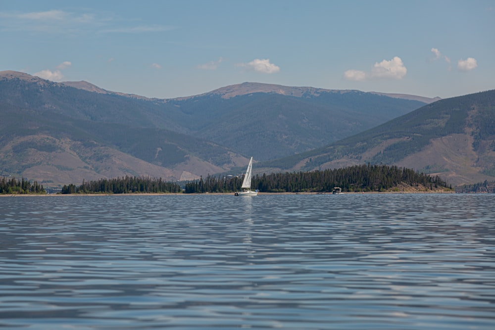 weißes Segelboot auf See in der Nähe von Green Mountains tagsüber