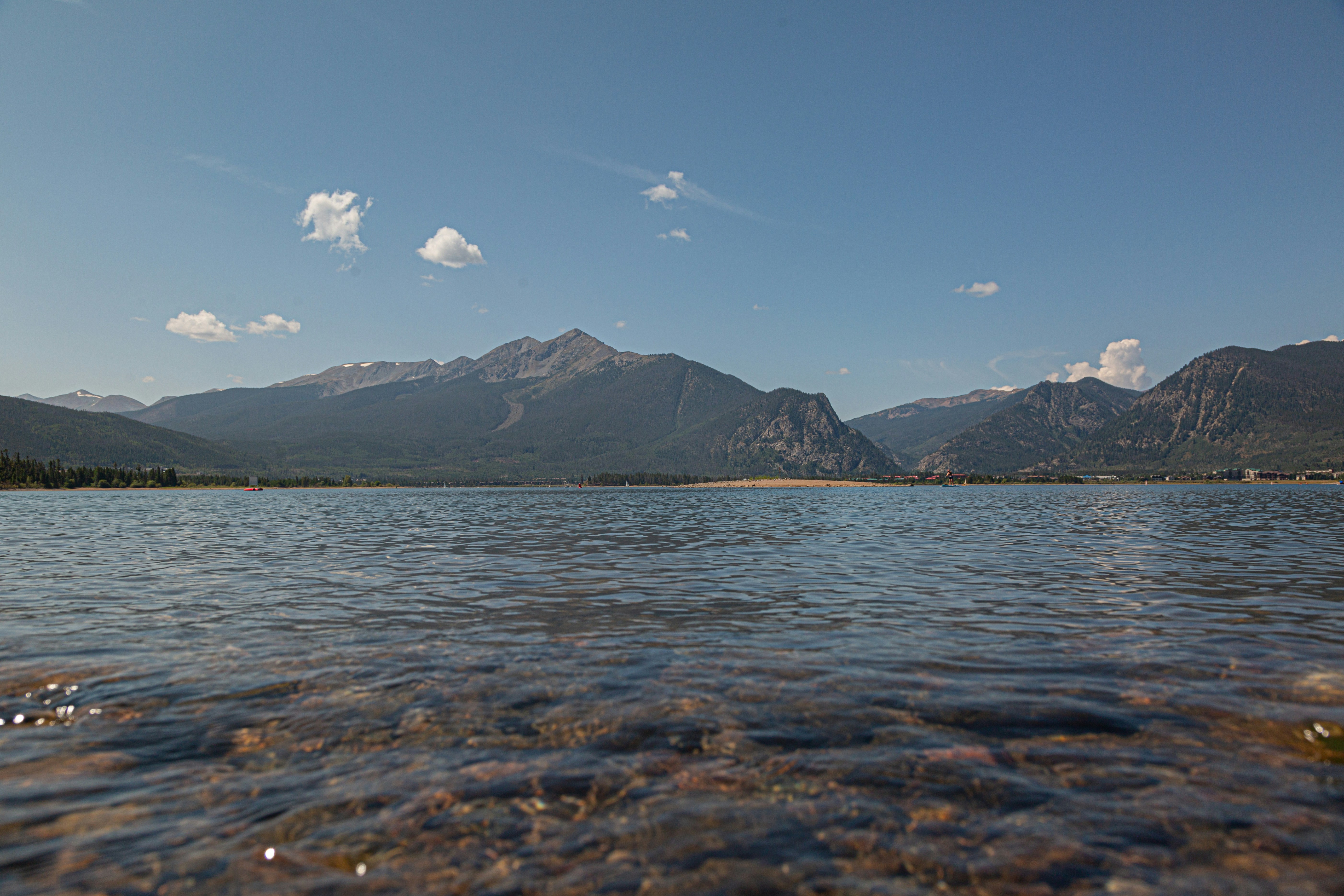 body of water near mountain under blue sky during daytime