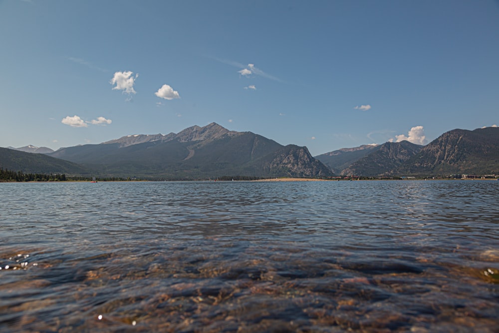 body of water near mountain under blue sky during daytime