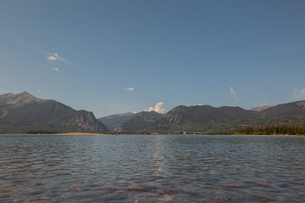 body of water near mountain under blue sky during daytime