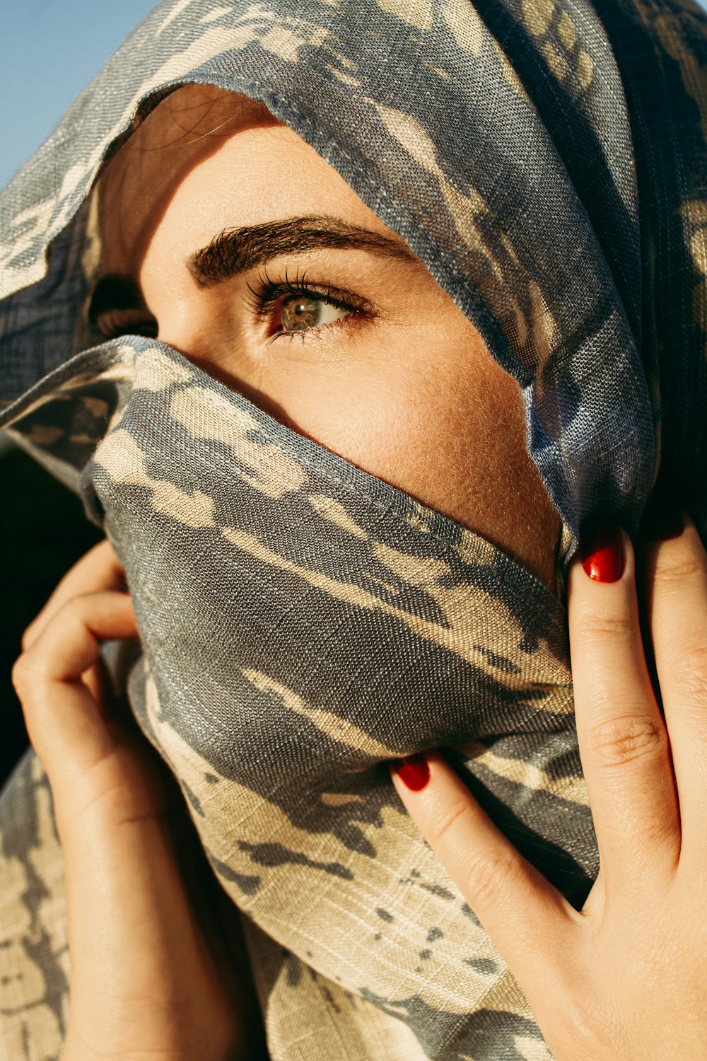 woman covering her face with gray and black camouflage textile