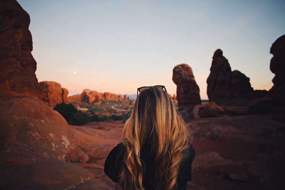 woman in black jacket standing on brown rock formation during daytime