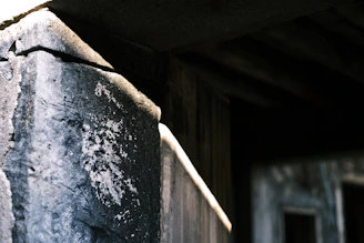 A close-up of a beautifully crafted stone pier cap atop a rustic brick pillar under soft sunlight.