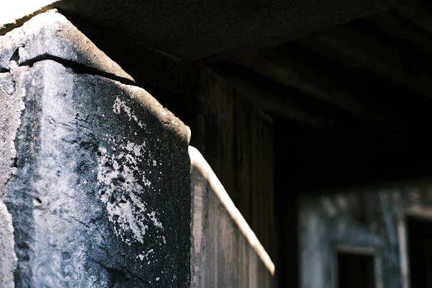 A close-up of a beautifully crafted stone pier cap atop a rustic brick pillar under soft sunlight.