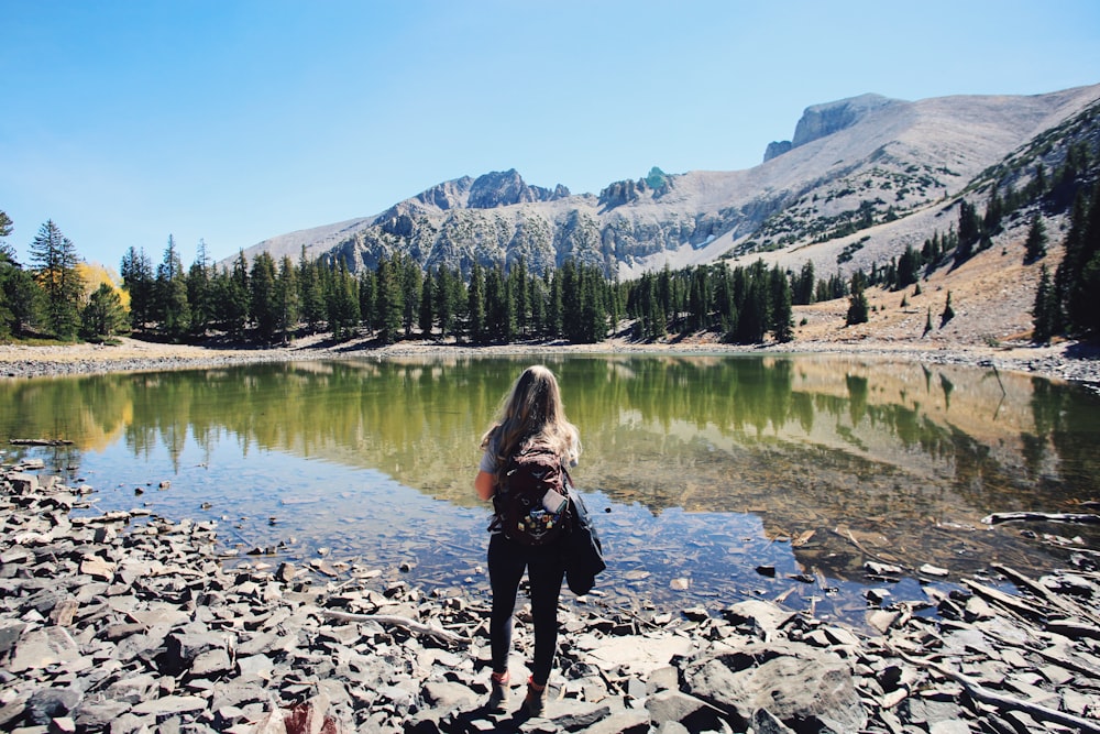 woman in black jacket standing on rocky shore during daytime