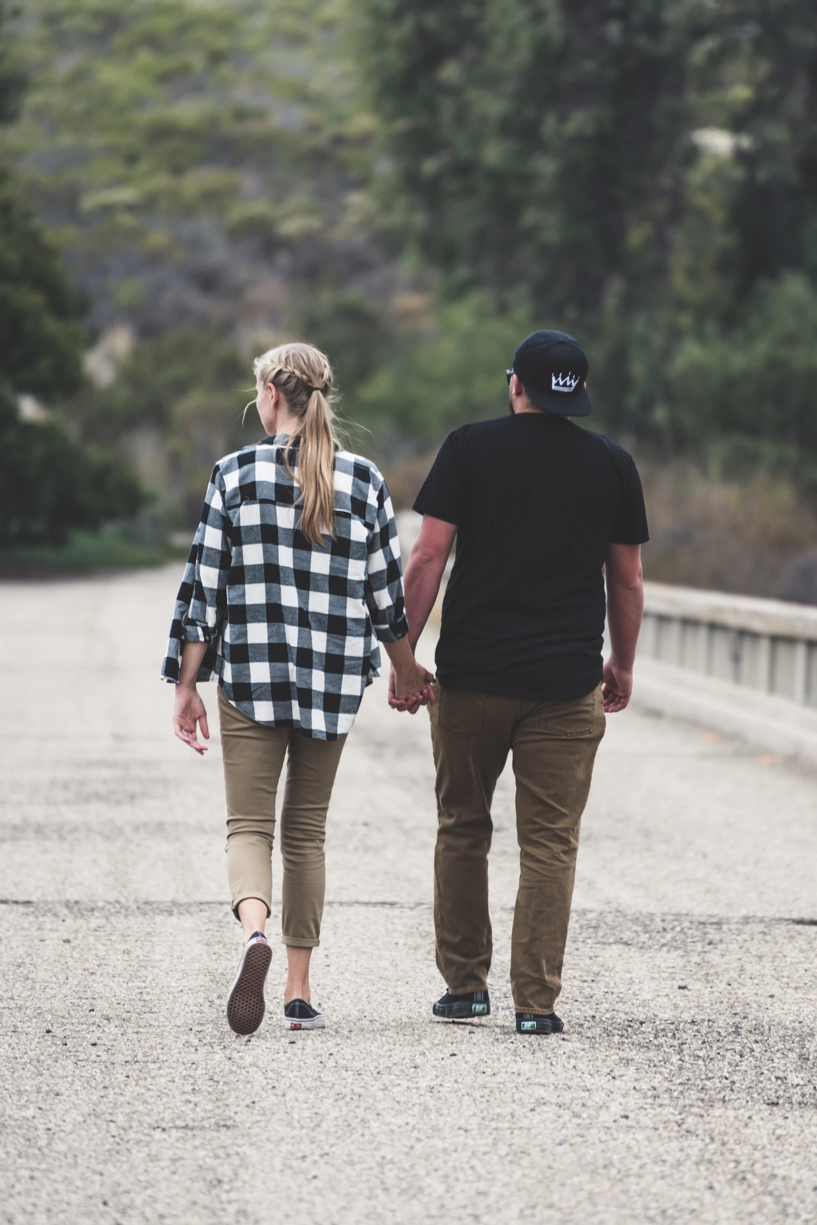 Un couple marche main dans la main sur une route bordée d'arbres