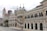 A historical building with intricate architecture, featuring large arched windows and a clock tower with a distinctive red dome. The structure is made of brick and stone, displaying a mix of colonial and Moorish designs.