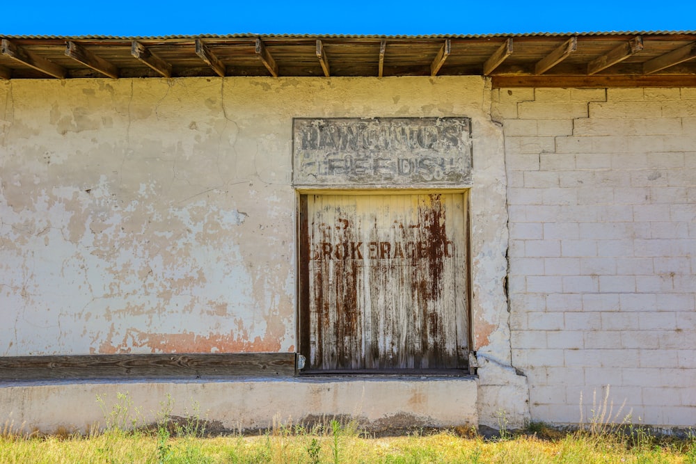 puerta de madera marrón sobre pared de hormigón blanco