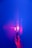 A hand holds a transparent object, illuminated by a vibrant pink and purple light against a deep blue background. The word 'PRISM' is projected repetitively on the hand and object, creating a dynamic play of light and shadow.