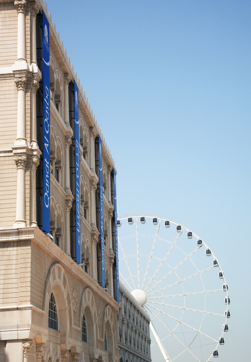 Weißes Riesenrad neben braunem Betongebäude tagsüber