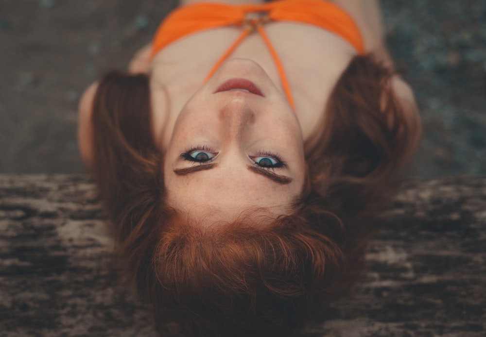 地面に横たわるオレンジ色のビキニを着た女性