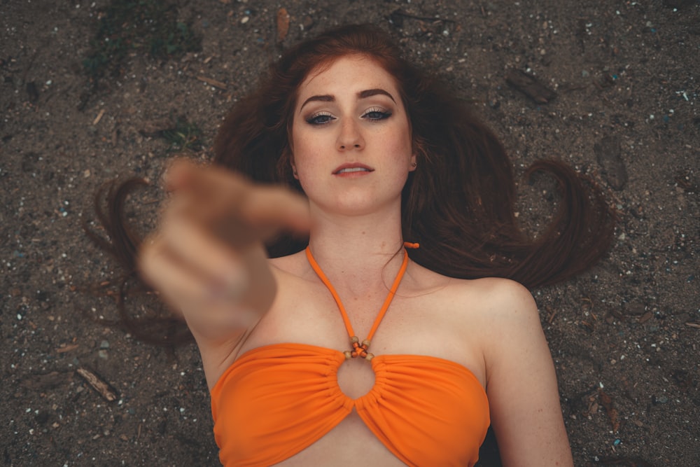 woman in orange bikini lying on ground