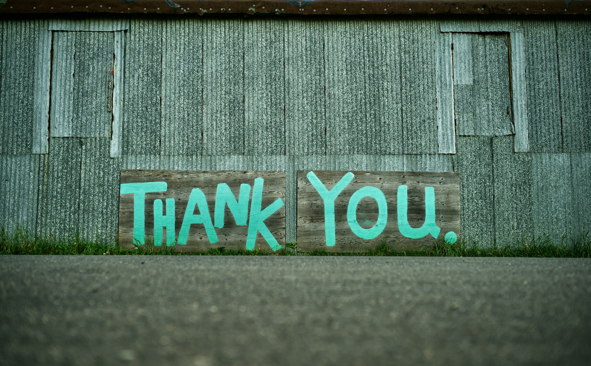 Metal sided building with Thank You painted on the side in blue paint.