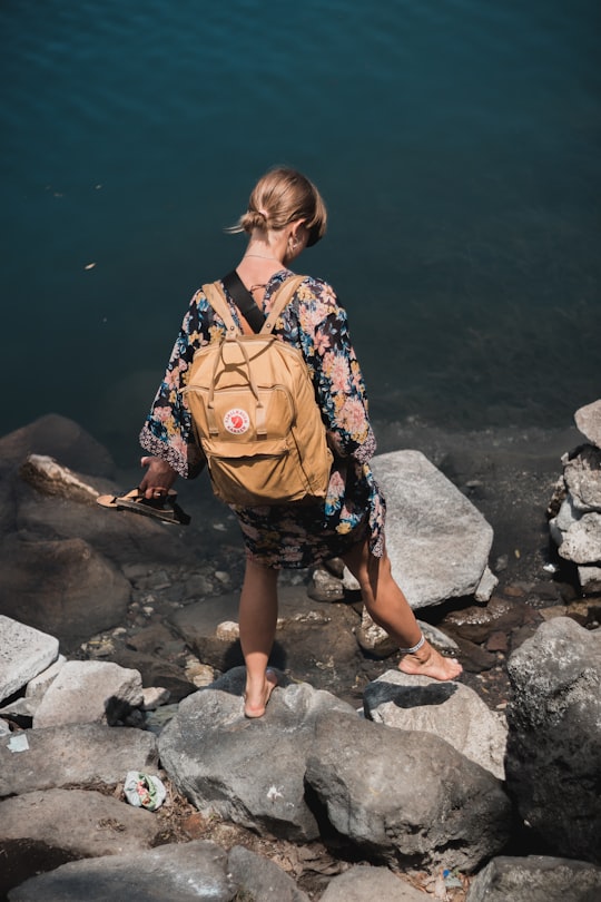 woman in blue red and white floral dress standing on rocky shore during daytime in Atitlán Guatemala