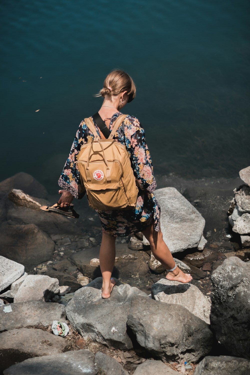 woman in blue red and white floral dress standing on rocky shore during daytime