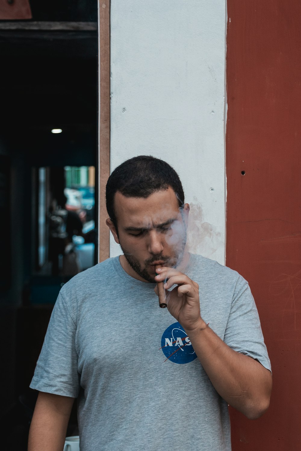 uomo in maglietta girocollo grigia che fuma sigaretta