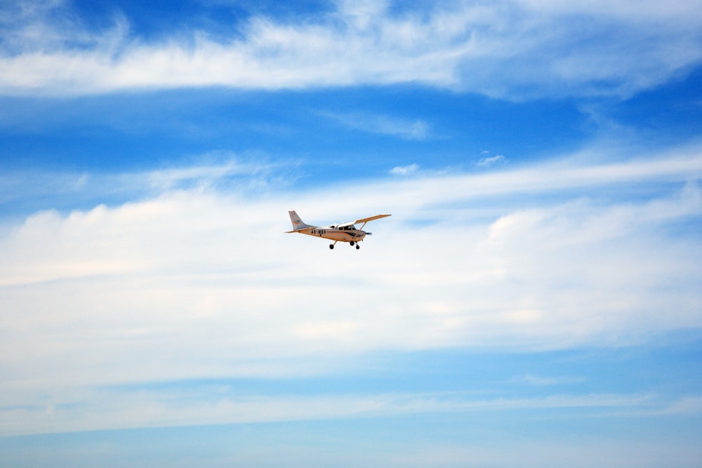 aeroplano bianco e nero che vola sotto il cielo blu durante il giorno