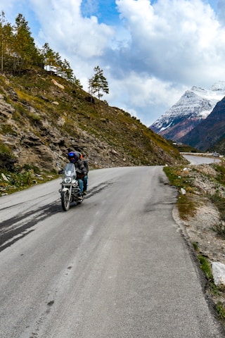 A rider on a motorcycle cruising along a scenic mountain road.