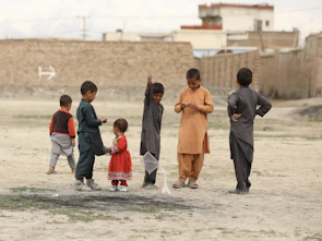 Children playing traditional rural games on a dusty village ground.