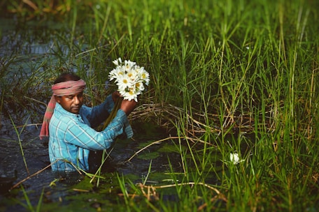 woman in blue denim jacket holding white daisy flower