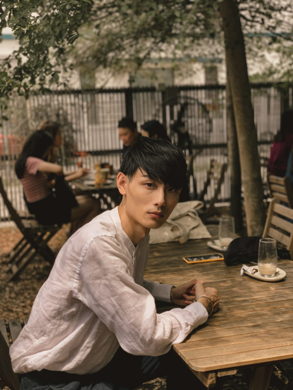 man in white dress shirt sitting on brown wooden table