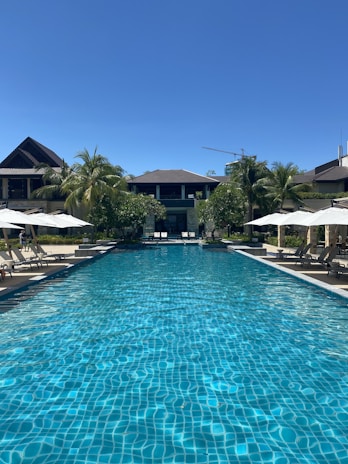 A luxurious beachfront hotel pool with loungers and a clear blue sky.