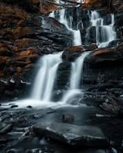 water falls on rocky shore during daytime