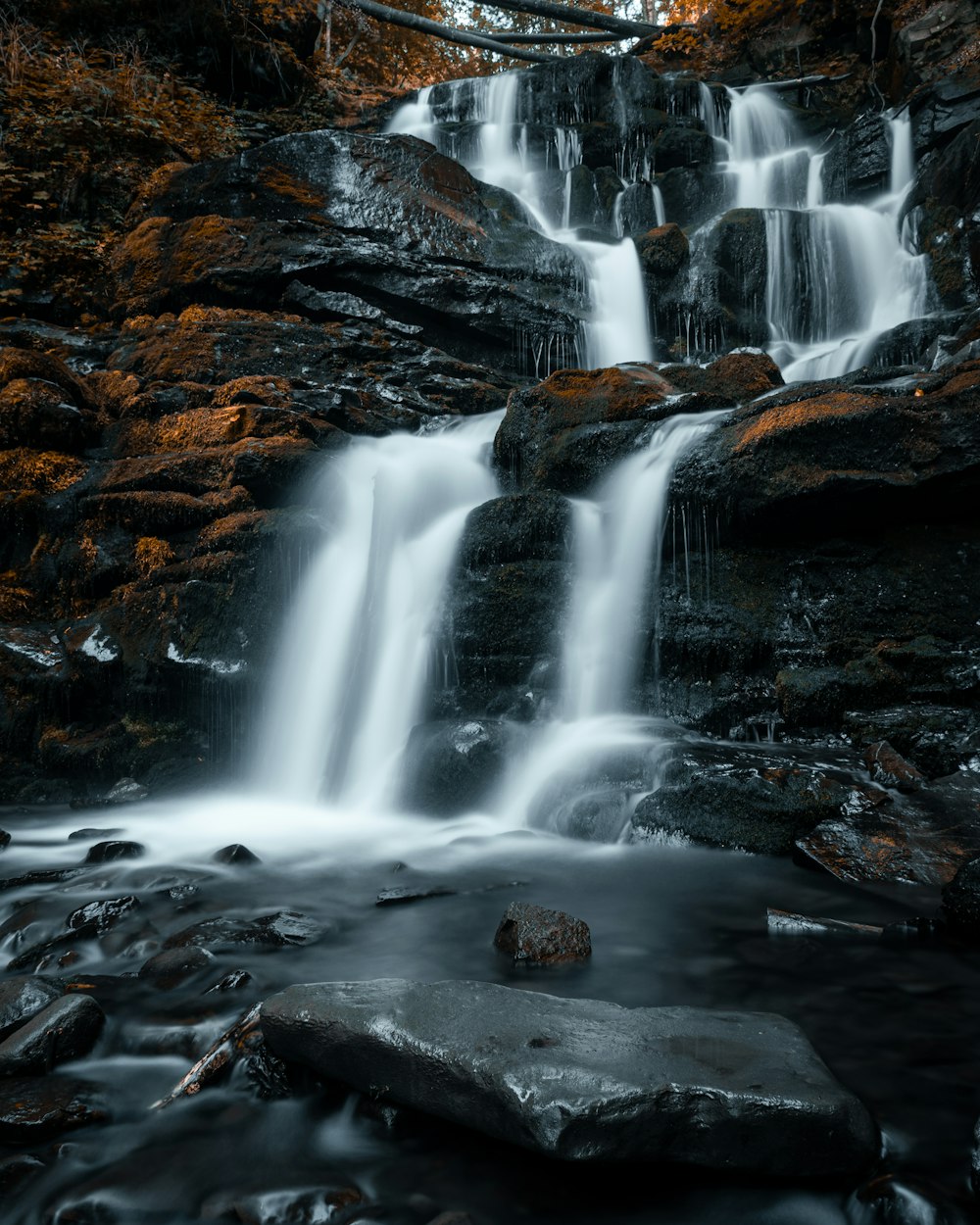 water falls on rocky shore during daytime