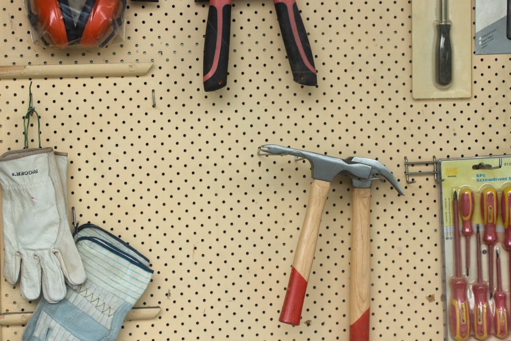 black and silver claw hammer beside red and black hand tool