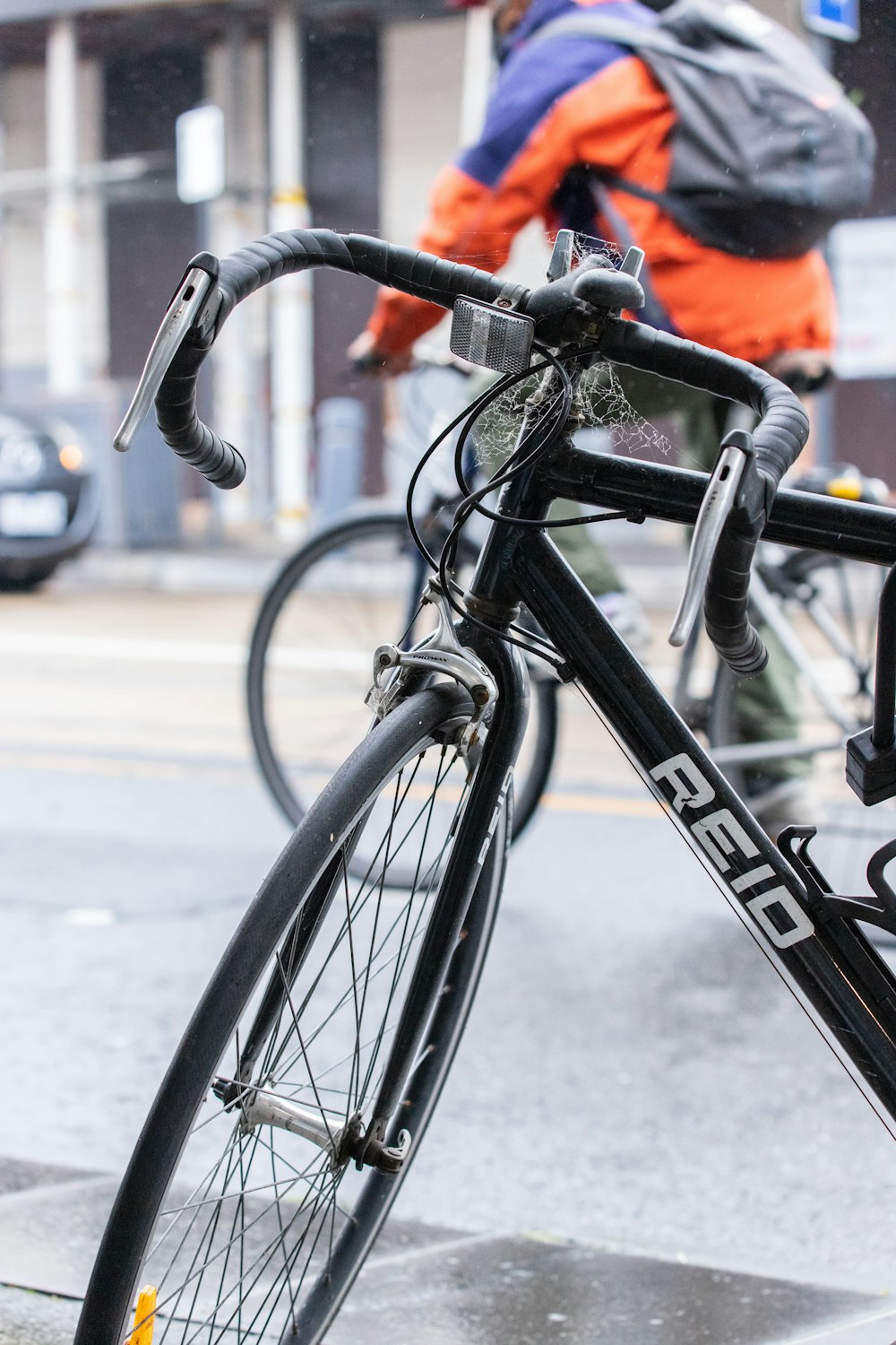 person in orange jacket riding black bicycle on road during daytime