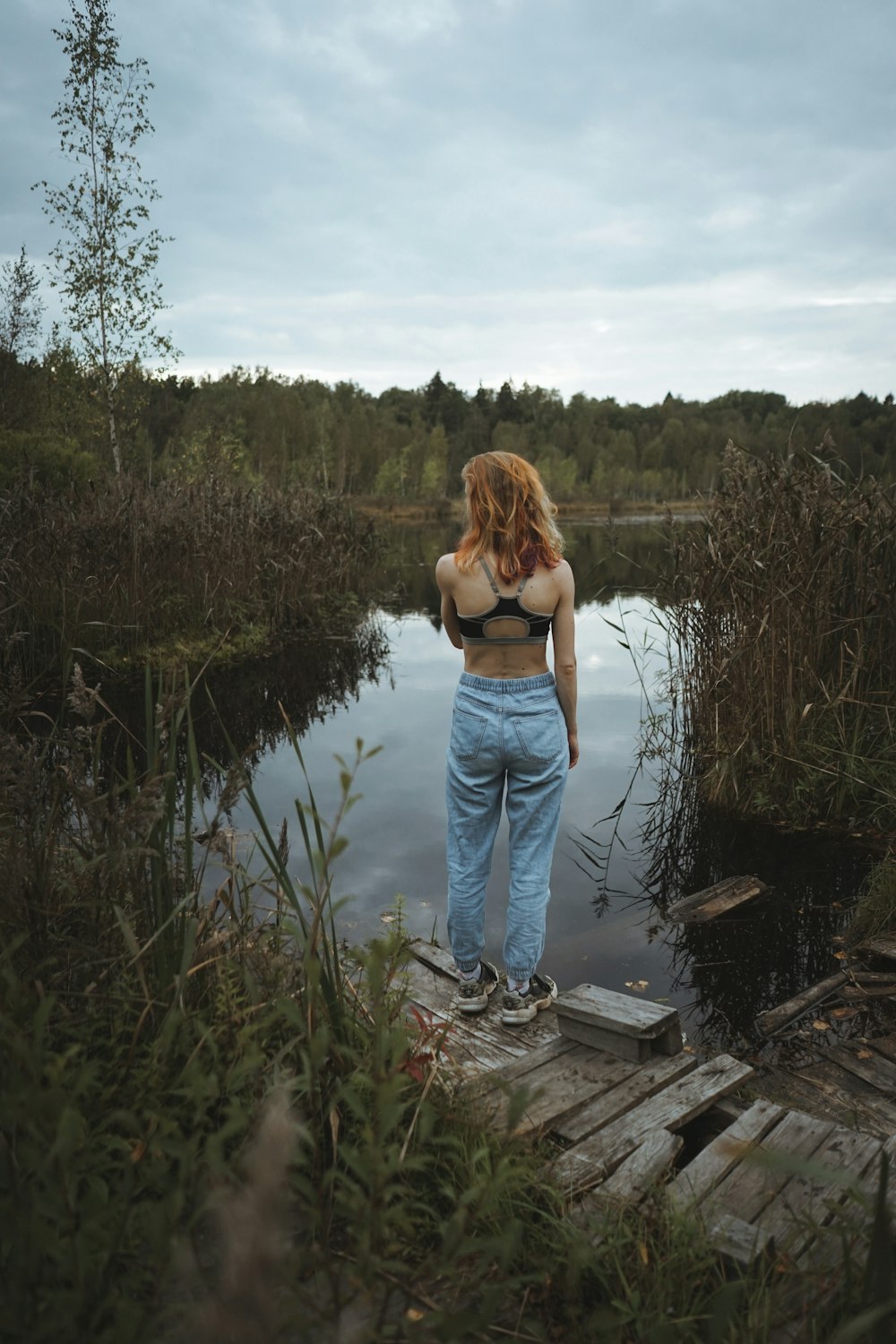 woman in blue denim jeans standing on dock during daytime