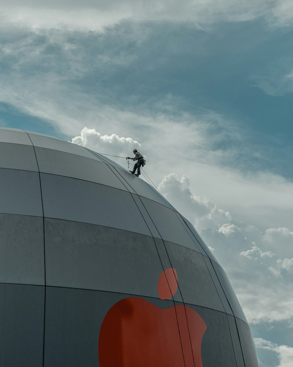 man in black jacket riding bicycle on brown round building under white clouds during daytime